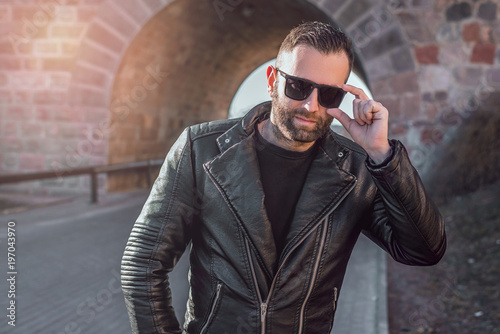 handsome attractive bearded model man in sunglasses and leather jacket.