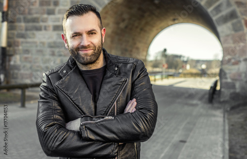 Handsome man with beard wearing leather Jacket smiling