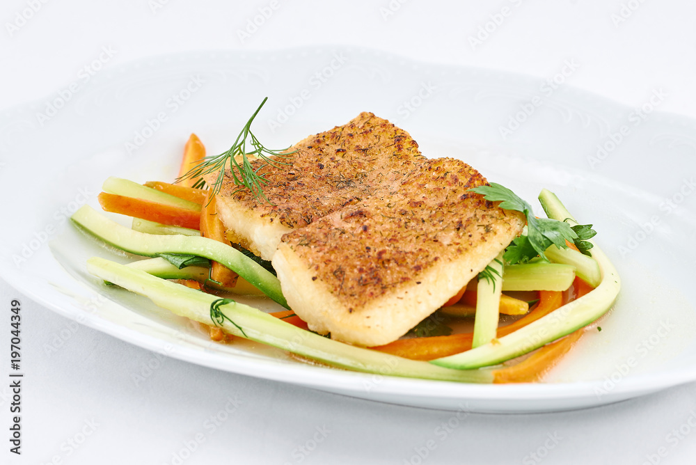 Delicious fried fish on fresh orange and green pepper strips on a white plate. Delicious fried fish on fresh orange and green pepper strips on a white plate.