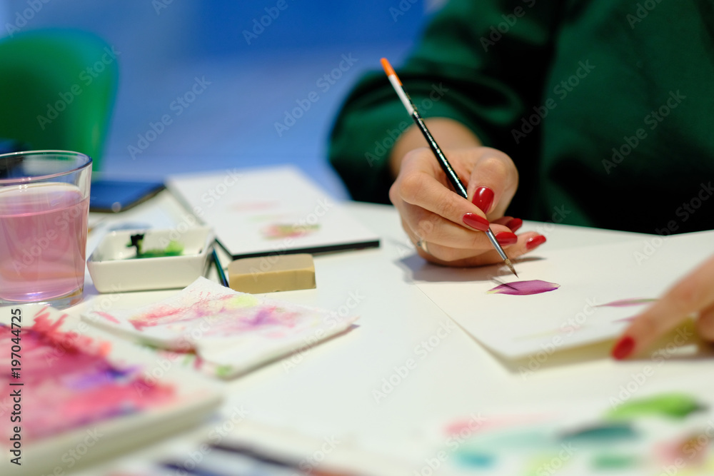 Woman painting with paint brush on paper in art studio Woman painting with paint brush on paper in art studio