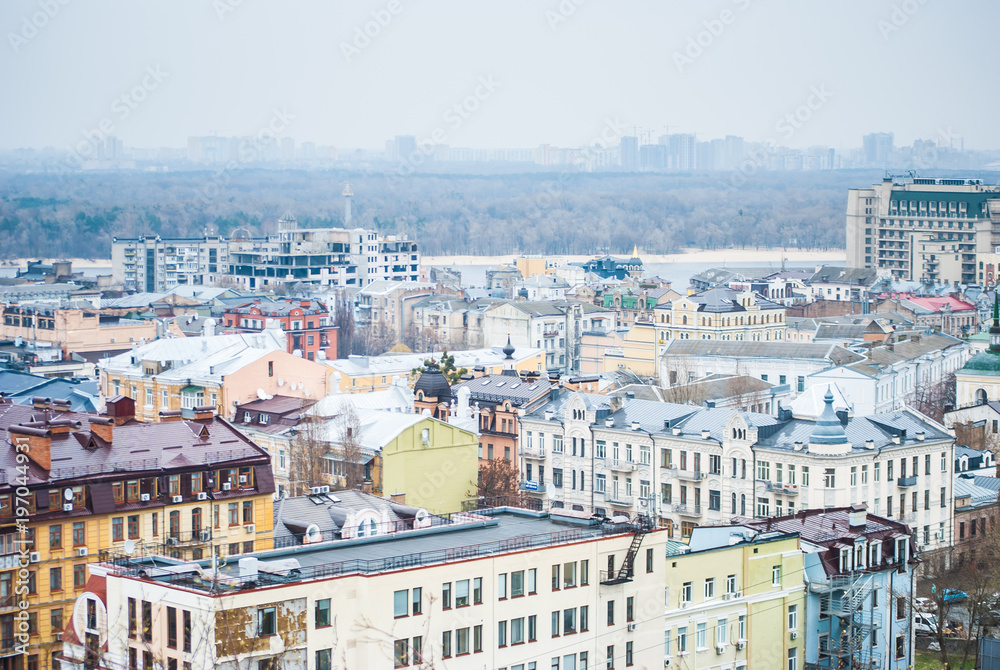 City of Kyiv (Kiev), capital of Ukraine, panorama. Colorful houses and Dnipro river on a background. Cloudy spring afternoon.
