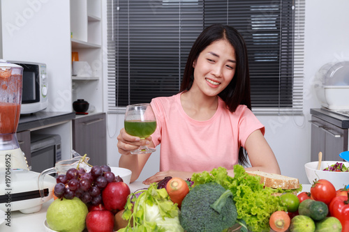 woman drinking vegetable juice in kitchen