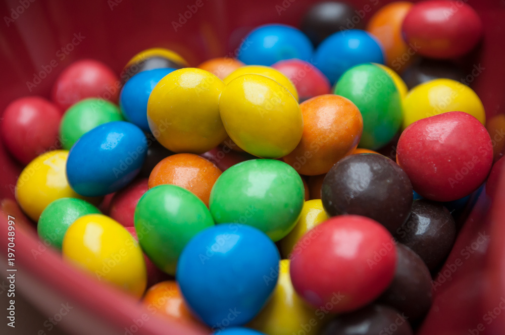 closeup of colorful chocolate candies in a red bowl in shaped heart closeup of colorful chocolate candies in a red bowl in shaped heart