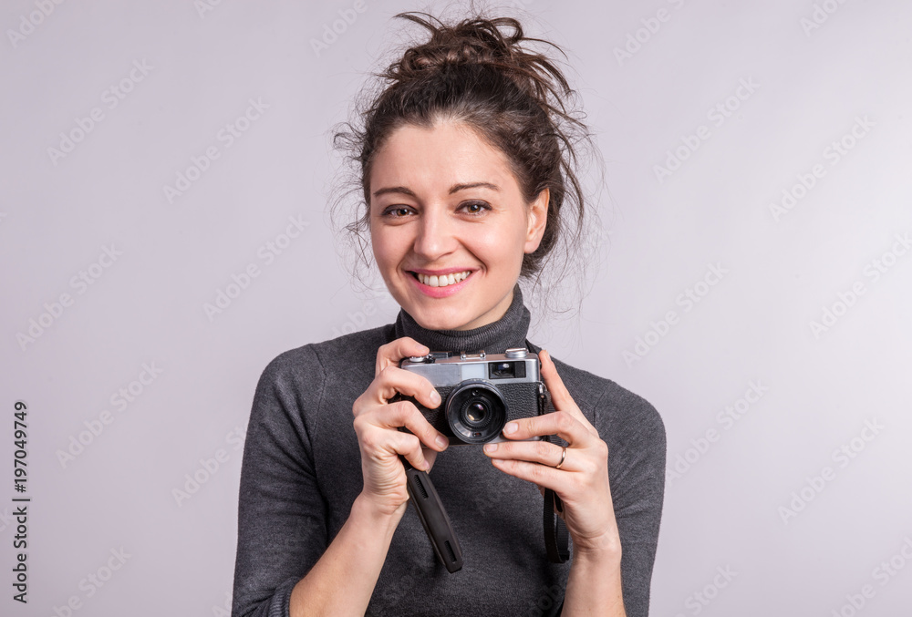 Portrait of a young woman with a camera in studio. Portrait of a young woman with a camera in studio.