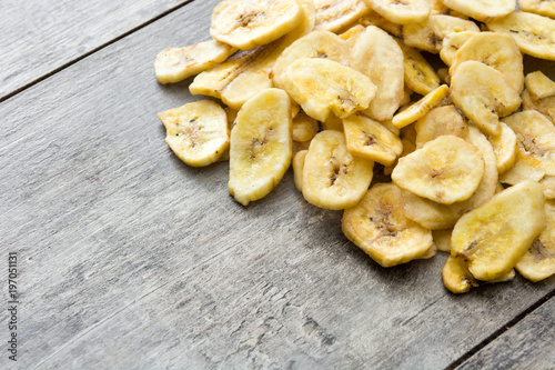 Banana chips on wooden table. Copyspace
