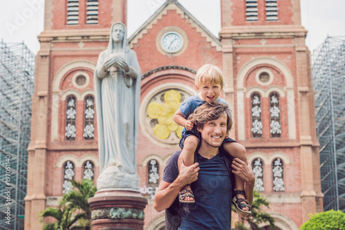 Father and son in the background Notre dame de Saigon Cathedral, build in 1883 in Ho Chi Minh city, Vietnam photo