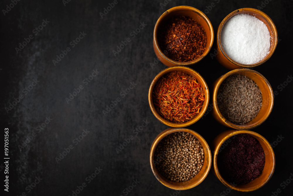 Set of spices on dark grey background. Food art concept. Composition of bottles with colored herbs and spices. Set of spices on dark grey background. Food art concept. Composition of bottles with colored herbs and spices.