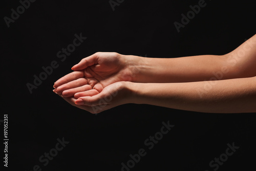 Woman keeping hands in cupped shape, cutout on black