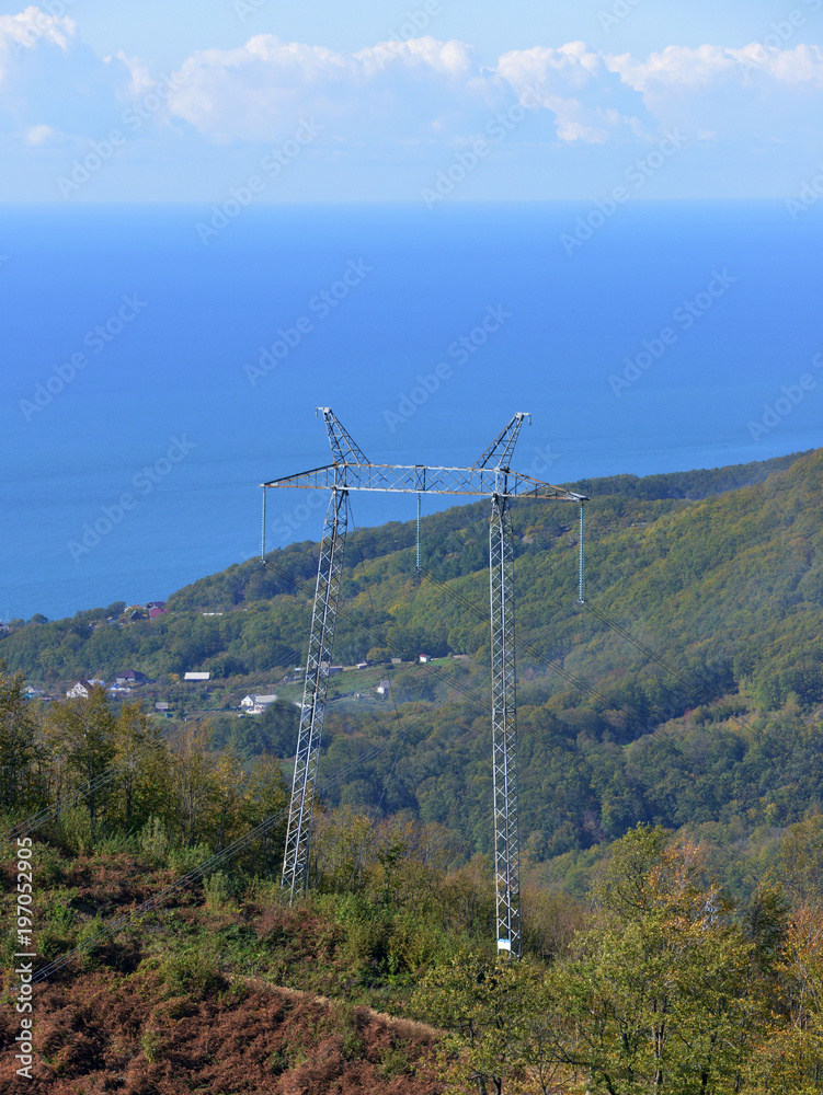 Aerial view of a electricity power line in beautiful mountain landscape against the sea