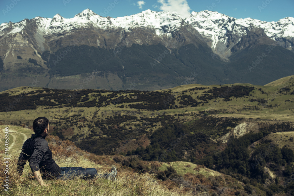 Hombre joven disfrutando de las vistas de un paisaje con montañas evadas en Nueva Zelanda