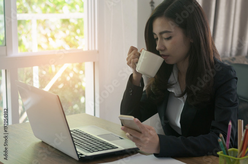 attractive business woman working on table with laptop and smartphone and drinking coffee.