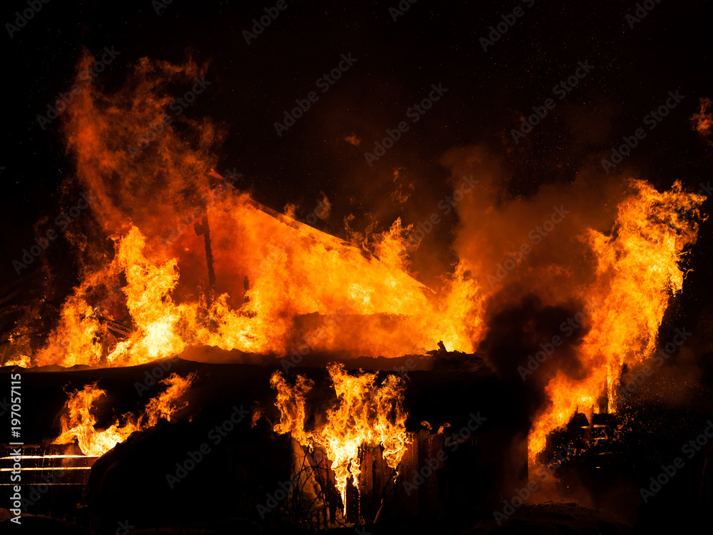 Obraz premium Burning fire flame on wooden house roof