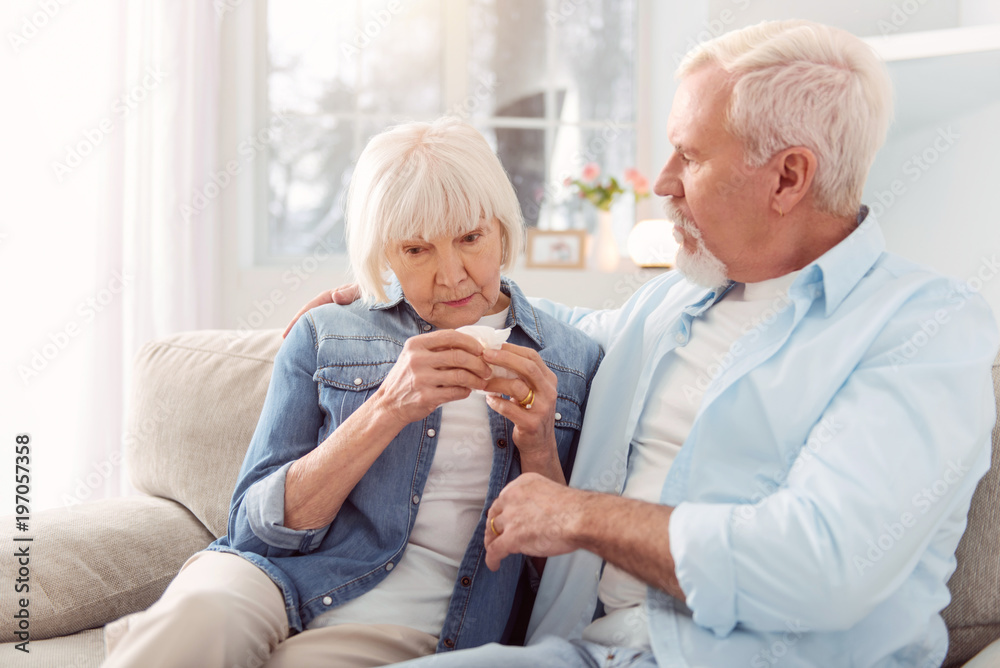 Calm down. Loving senior man sitting on the couch next to his wife, hugging and consoling her while she crying having heard bad news Calm down. Loving senior man sitting on the couch next to his wife, hugging and consoling her while she crying having heard bad news