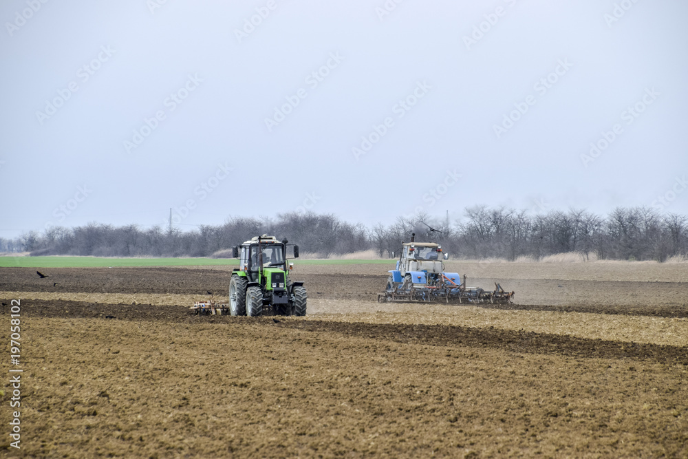 Lush and loosen the soil on the field before sowing. The tractor plows a field with a plow