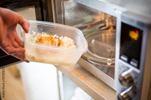 Photography Young man hands giving the food into the microwave for warm up