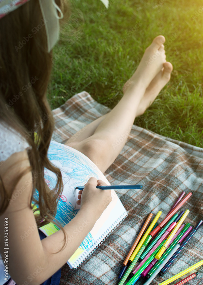 Little girl with hat, draws sitting in the park. Warm, sunny day. Art. Summer camp