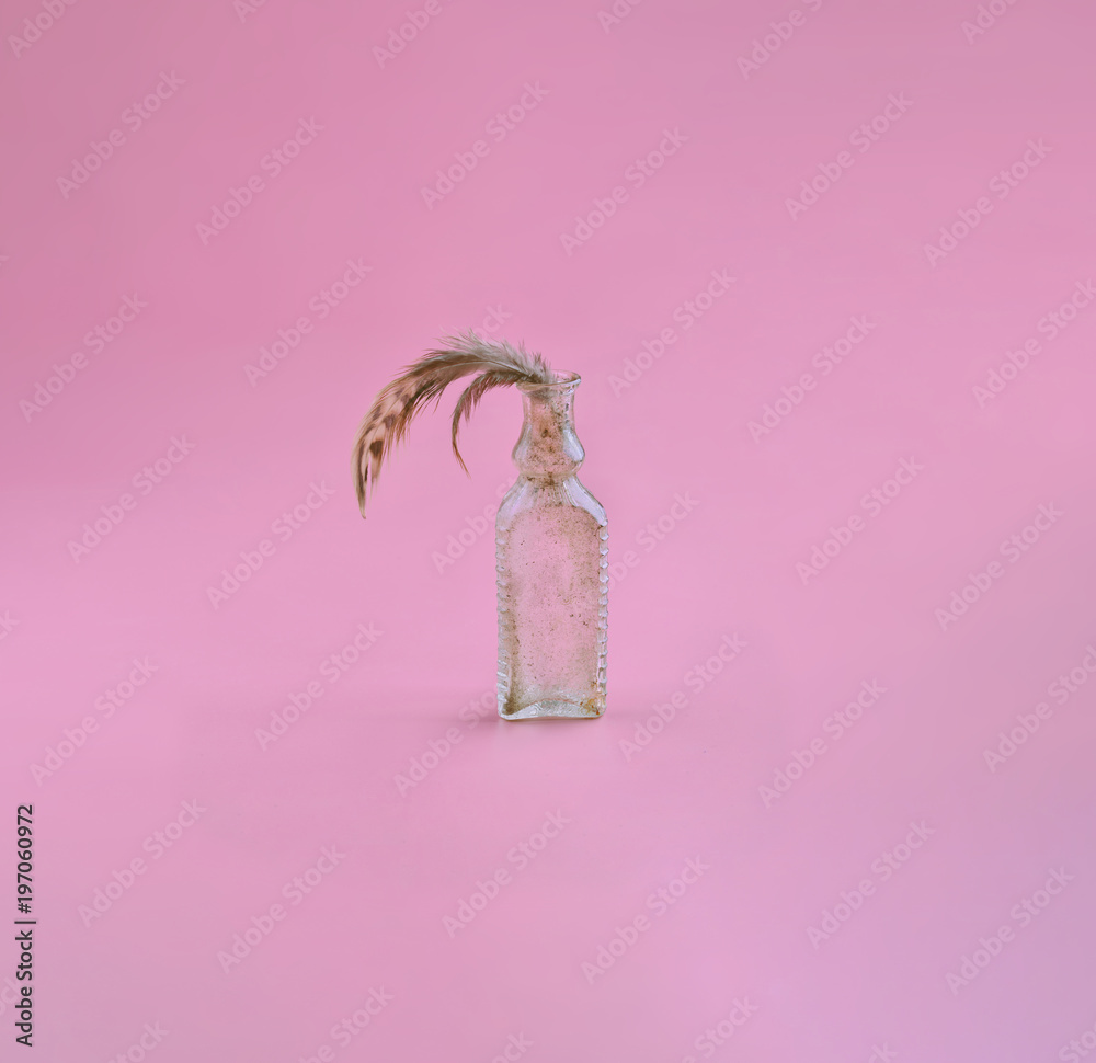 Minimalistic bird feather in a bottle neck on a purple background. Perfume concept. Vintage pastel colors. Minimalistic bird feather in a bottle neck on a purple background. Perfume concept. Vintage pastel colors.