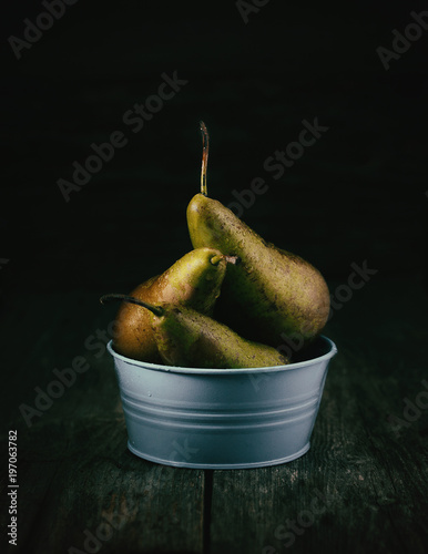 3 pears conference in light basin in rustic style,  dark wood texture