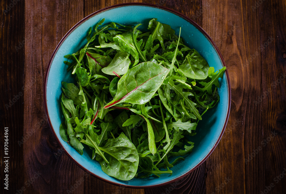 Fresh green salad with spinach,arugula, mangold and lettuce on dark wooden background Fresh green salad with spinach,arugula, mangold and lettuce on dark wooden background