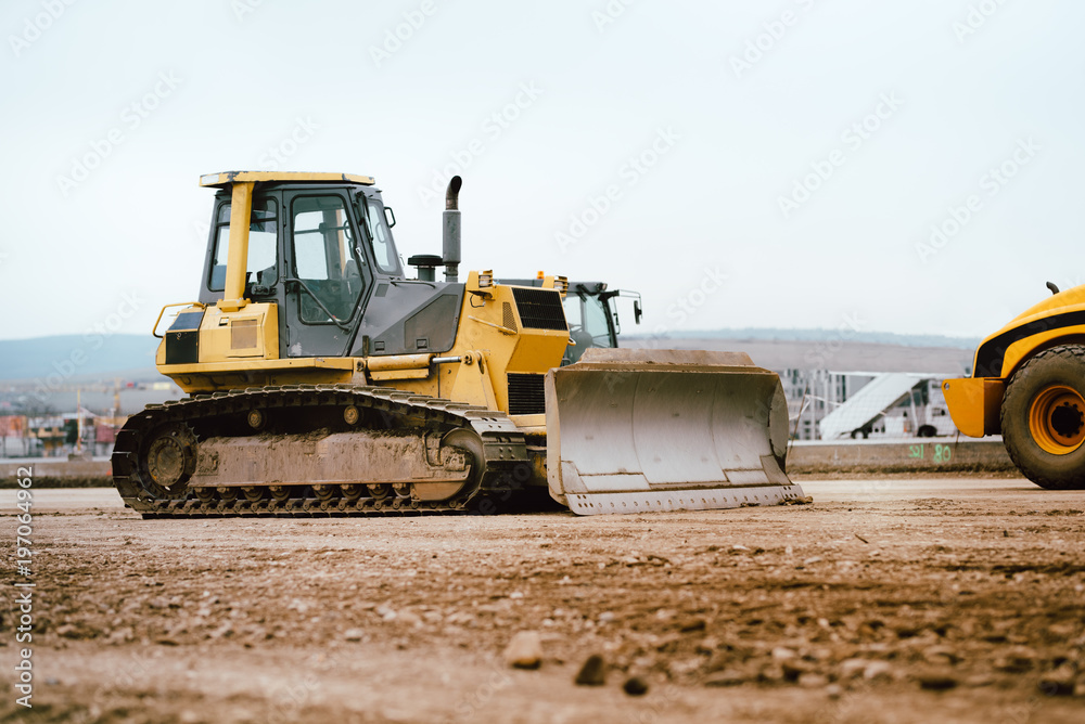 industrial building construction site mini bulldozer levelling and moving soil during highway building