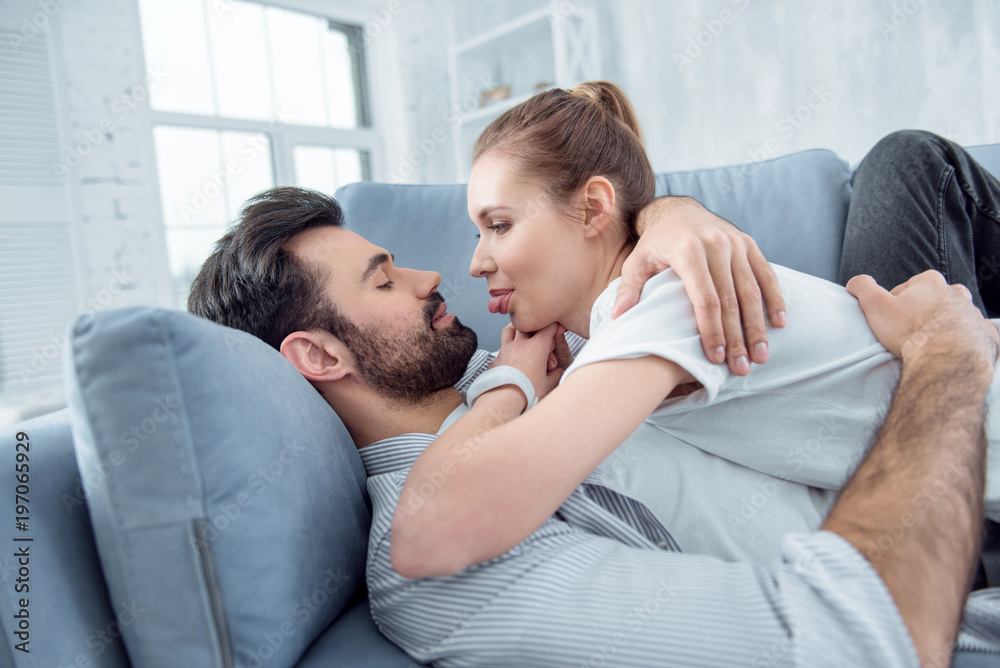 Lets joke. Joyful female person lying on her boyfriend and showing tongue while having rest Lets joke. Joyful female person lying on her boyfriend and showing tongue while having rest