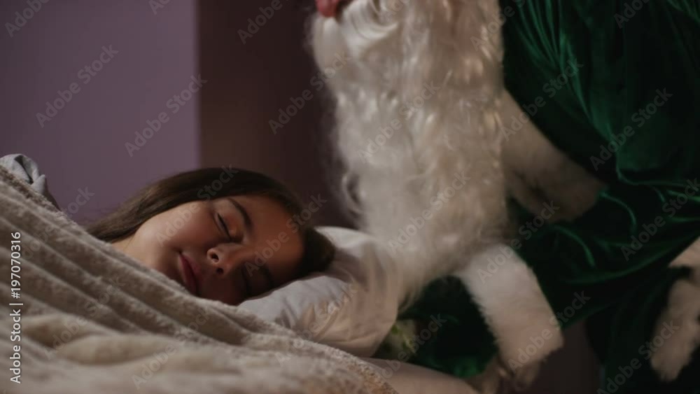 Santa Claus putting a gift box under the pillow of a little girl, and fondling her head, while she is sleeping. Shot on RED Cinema Camera Santa Claus putting a gift box under the pillow of a little girl, and fondling her head, while she is sleeping. Shot on RED Cinema Camera