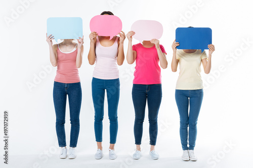 Anonymity project. Nice positive young women standing against white background and hiding their face while participating in the new project