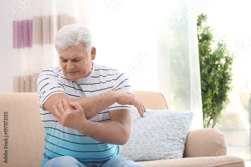 Mature man suffering from elbow pain at home