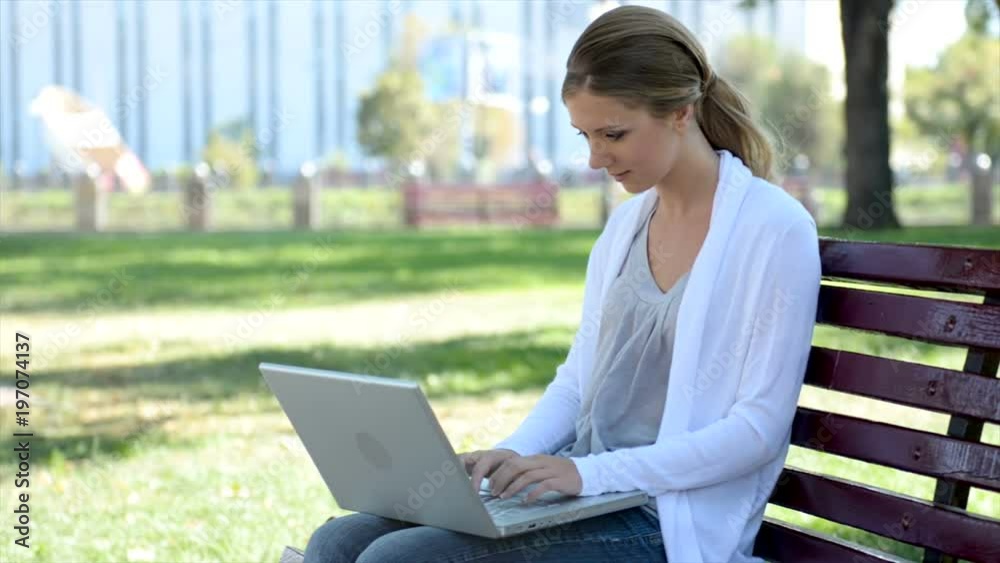 Young pretty woman sitting on bench with laptop Young pretty woman sitting on bench with laptop
