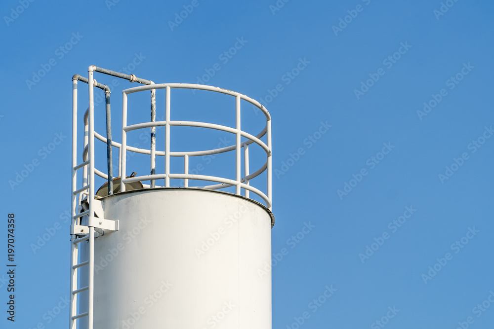 Large white water tank with blue sky background.