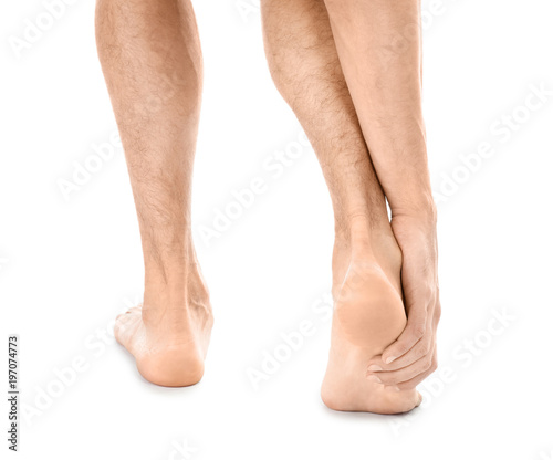 Young man suffering from pain in foot on white background