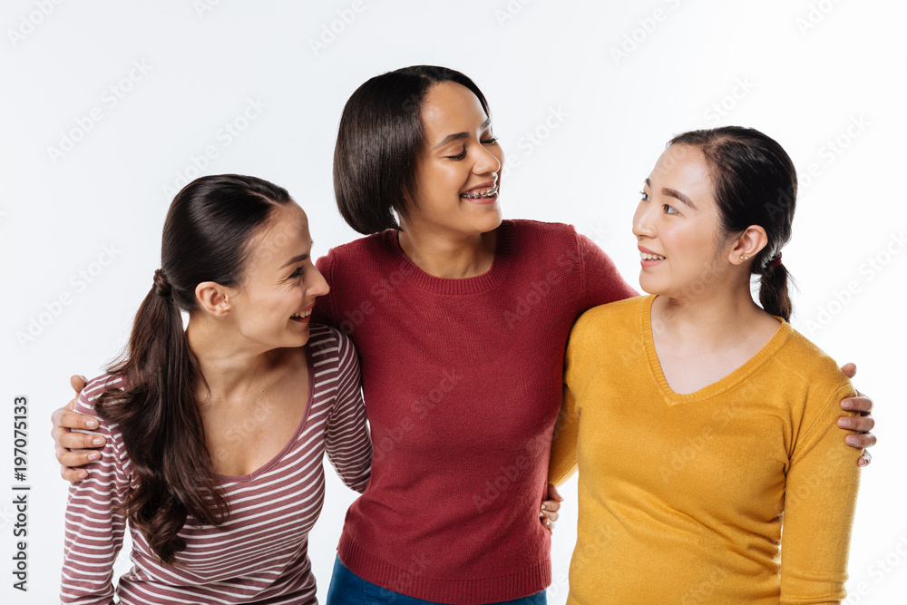Great mood. Delighted positive nice friends standing together and looking at each other while being in a great mood Great mood. Delighted positive nice friends standing together and looking at each other while being in a great mood