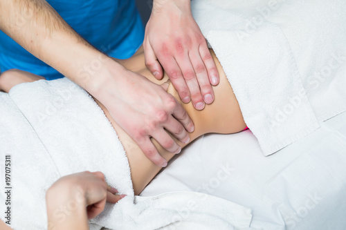 Masseur conducts anti-cellulite massage of the woman abdomen