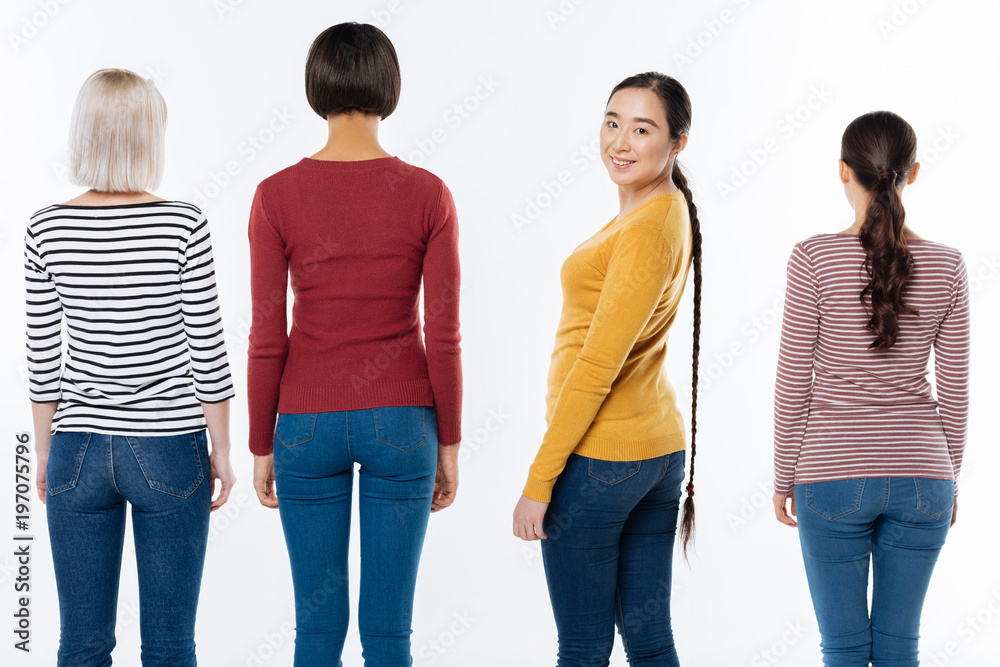 Obraz premium Wonderful mood. Positive joyful nice woman standing among her friends and turning to you while feeling happy
