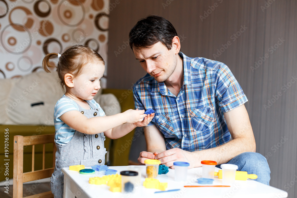 Picture of a father and daughter playing with color play dough and cutters. Having fun with colorful modeling clay. Creative kids molding at home. Children play with plasticine or dough. Picture of a father and daughter playing with color play dough and cutters. Having fun with colorful modeling clay. Creative kids molding at home. Children play with plasticine or dough.