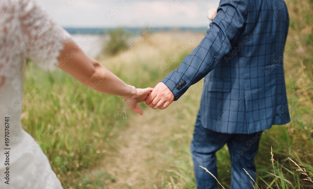 The groom leads the bride's hand. Wedding walk. The groom leads the bride's hand. Wedding walk.