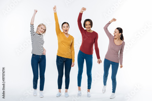 Our achievement. Joyful nice attractive women standing together and saying yes while being happy about their achievement
