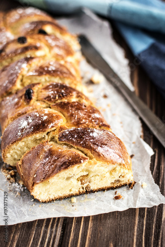 Homemade braided sweet bread with raisins on a wooden background