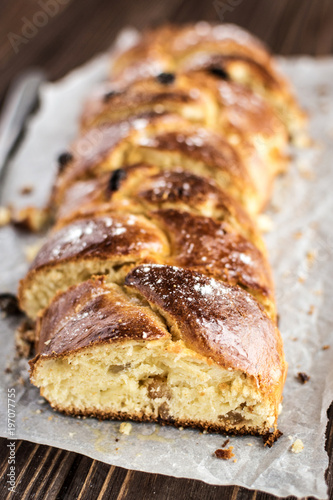 Homemade braided sweet bread with raisins on a wooden background
