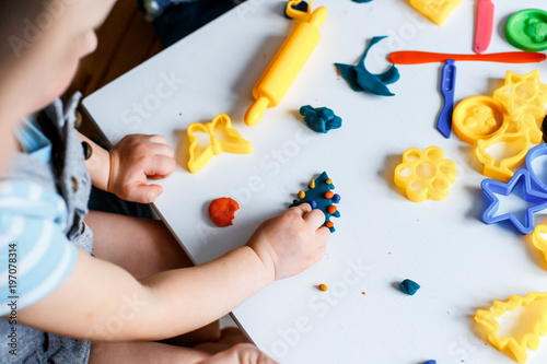 Close up picture of a child playing with color play dough and cutters. Having fun with colorful modeling clay. Creative kids molding at home. Children play with plasticine or dough.