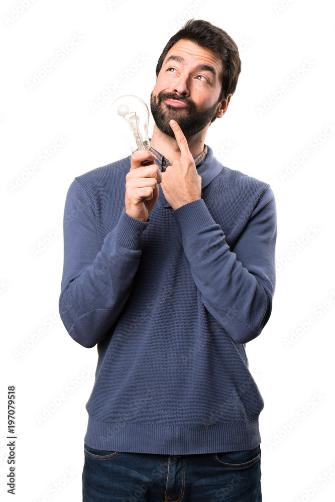 Handsome brunette man with beard holding a supermarket cart toy on white background