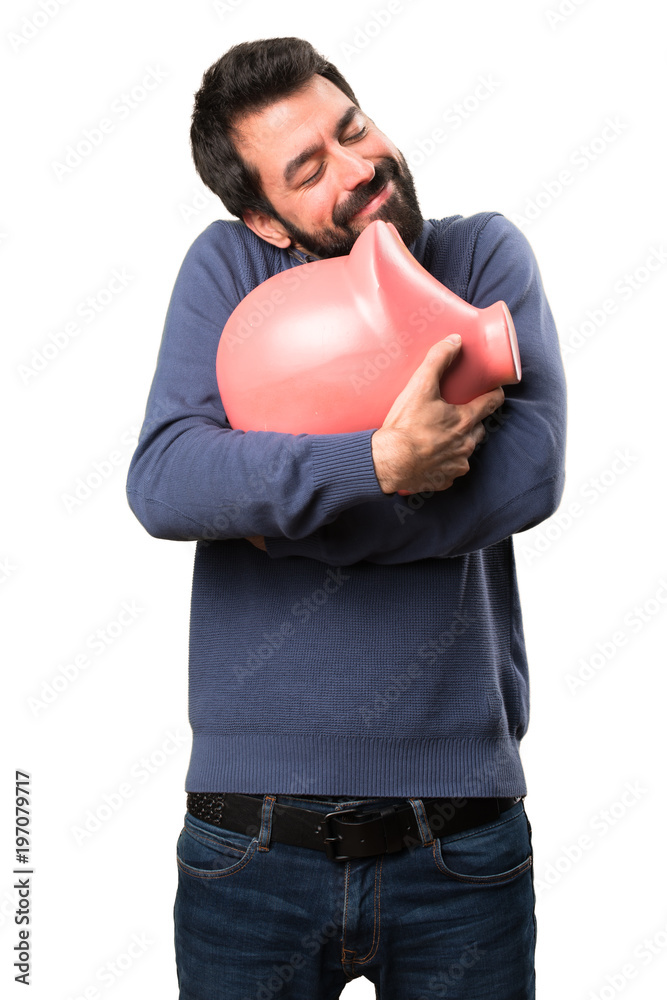 Happy Handsome brunette man with beard holding a piggybank on white background Happy Handsome brunette man with beard holding a piggybank on white background