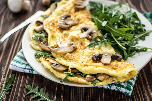 Cuadro en lienzo Omelette with mushrooms and arugula on a wooden background