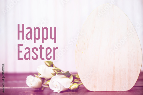 Happy easter. close-up of wooden easter egg and rose flowers on wooden background. template with copy space. eeaster greeting card with free space photo