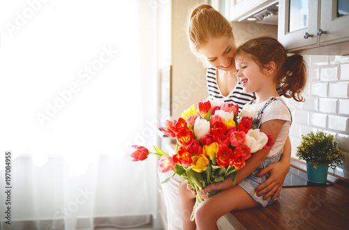 happy mother's day! child daughter   gives mother a bouquet of flowers to tulips