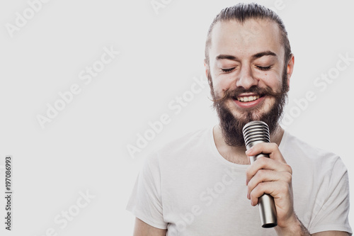 Boy Rocking Out. Image of a handsome bearded man singing to the microphone. Emotional portrait of an attractive guy with a beard on a white background