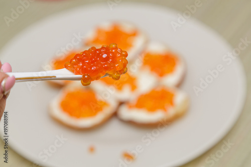 On a white ceramic spoon is the red caviar