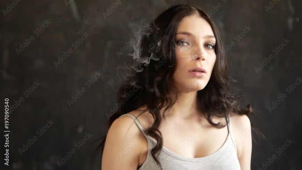 Close up of woman mouth smoking. The girl slowly and sexually releases smoke from an electronic cigarette