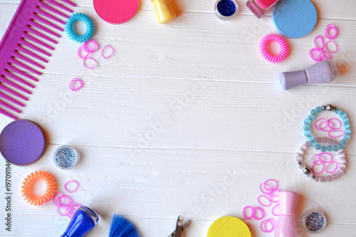 Colorful and bright cosmetics. Beauty care tools. Beauty salon. Girl's paradise. Nail polishes, sequins, pink hair bands and comb on the white wooden desk. Bright still life of beauty instruments.