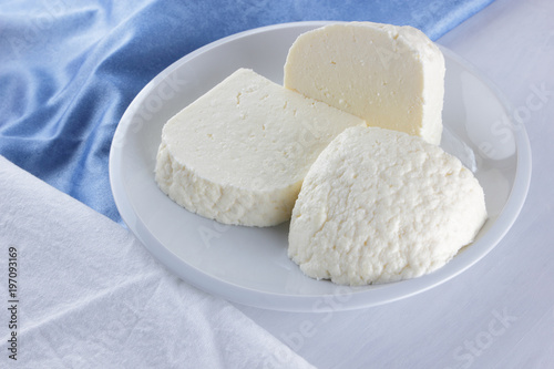 Cheese, cheese on a white plate, a glass of yogurt, minimalism, top view, copy space, dairy products on a white napkin, blue cloth, cheese pattern, French breakfast, white cheese on a white background